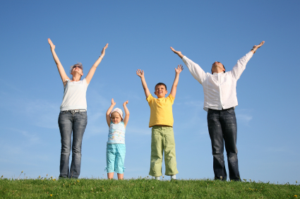 family of four on grass with hands up